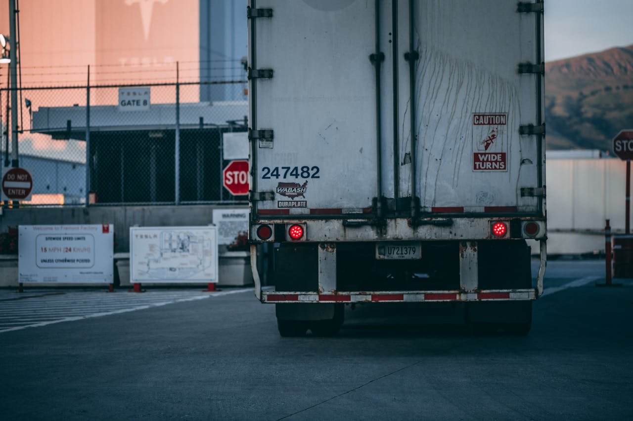 why-choose-us Semi truck parked at a loading dock with visible caution signs and industrial surroundings.